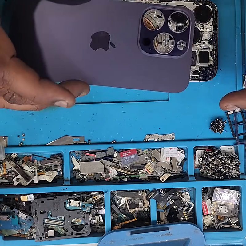 Technician fitting a replacement back glass onto an opened iPhone at the Vels Mobiles bench