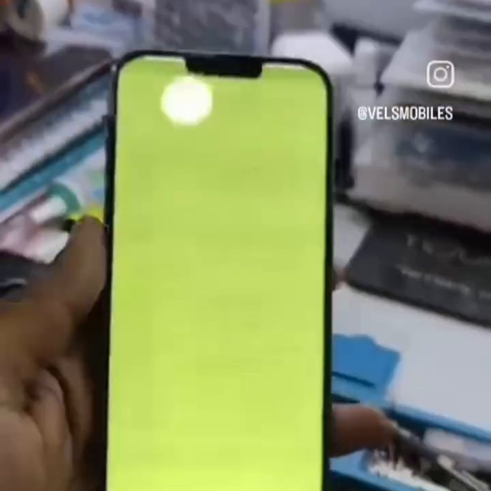 A replacement iPhone display running a full-screen colour test after fitting